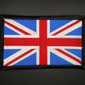 May include: Embroidered Union Jack patch, the flag of the United Kingdom. The patch features a blue background with red and white diagonal stripes and a red cross. The rectangular patch has a black border.