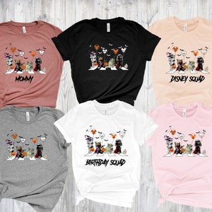 Puede incluir: Una colecci&oacute;n de seis camisetas de manga corta en varios colores, cada una con un gr&aacute;fico de personajes de Star Wars cruzando una calle, con globos tem&aacute;ticos de Halloween y Disney. Las camisetas tienen el texto "MOMMY", "DISNEY SQUAD" y "BIRTHDAY SQUAD".