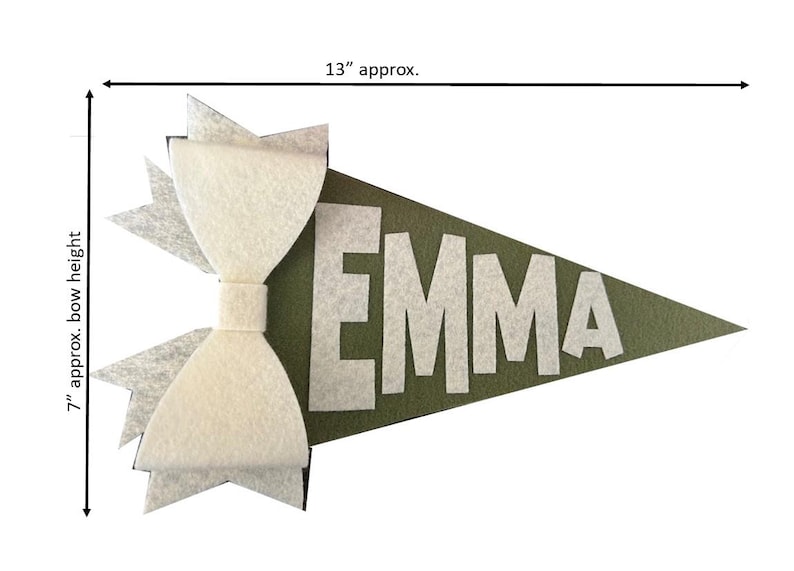 Może przedstawiać: Zielony proporzec z filcu z białą kokardą z filcu i imieniem "EMMA" w białych filcowych literach. Proporzec ma około 33 cm długości i 18 cm wysokości.