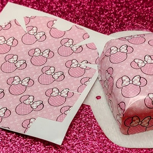May include: A pink and white patterned paper box with a Minnie Mouse design. The box is folded flat and ready to be assembled.