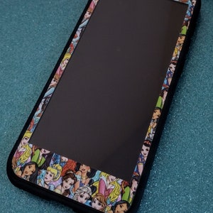 May include: A black phone case with a clear back and a border of Disney Princesses. The princesses are all different colors and have different expressions.