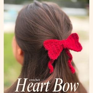 May include: A red crochet heart bow hair tie is shown in the hair of a person with brown hair. The image text reads "Heart Bow HAIR TIE", "Highly Customizable" and "Beginner Friendly".