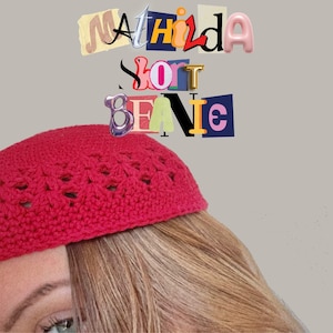 Puede incluir: Un gorro de punto rojo con un patrón de encaje. El gorro lo lleva una persona con el pelo largo y rubio. El texto "Mathilda Short Beanie" es visible en el fondo.