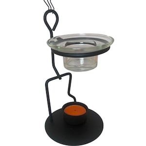 May include: Black metal candle holder with a clear glass dish and a small, round candle. The candle holder has a decorative design with a loop and curved accents. The candle is orange.