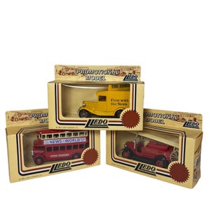 Pode incluir: Três veículos de brinquedo vintage em suas caixas originais. O conjunto inclui um caminhão amarelo com "THE TIMES", um ônibus de dois andares vermelho com "NEWS WORLD LONDON TRANSPORT" e um caminhão de bombeiros vermelho. Cada caixa é rotulada como "PROMOTIONAL MODEL".