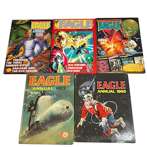 May include: A selection of vintage "Eagle Annual" comic books, featuring vibrant covers with space-themed illustrations. The covers showcase characters in space suits and alien creatures. Titles include "1988", "1985", "1983", "1973", and "1965".