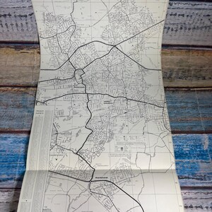 以下が含まれることがあります： ロムフォード、ホーンチャーチ、レインハム地域の詳細な道路網が描かれた白黒の印刷地図。地図にはグリッドシステム、左側の道路索引、さまざまな道路の種類やランドマークを示す凡例が含まれています。