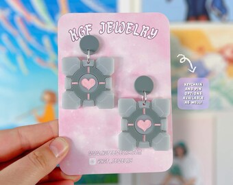 Pendientes, llaveros y broches de acrílico hechos a mano con la imagen del videojuego Companion Cube.