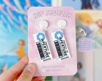 Pendientes, llaveros y broches de acrílico hechos a mano con el tema del videojuego Portal Tag.