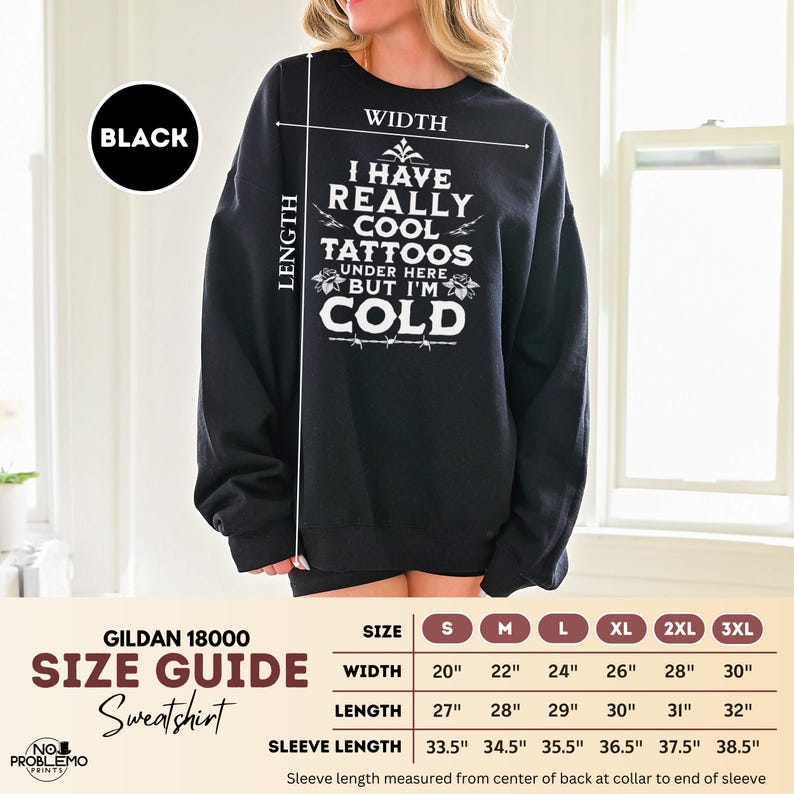 May include: A black crewneck sweatshirt featuring white text that reads I HAVE REALLY COOL TATTOOS UNDER HERE BUT I'M COLD. A size guide chart is included, listing widths from 20 to 30 inches, lengths from 27 to 32 inches, and sleeve lengths from 33.5 to 38.5 inches.
