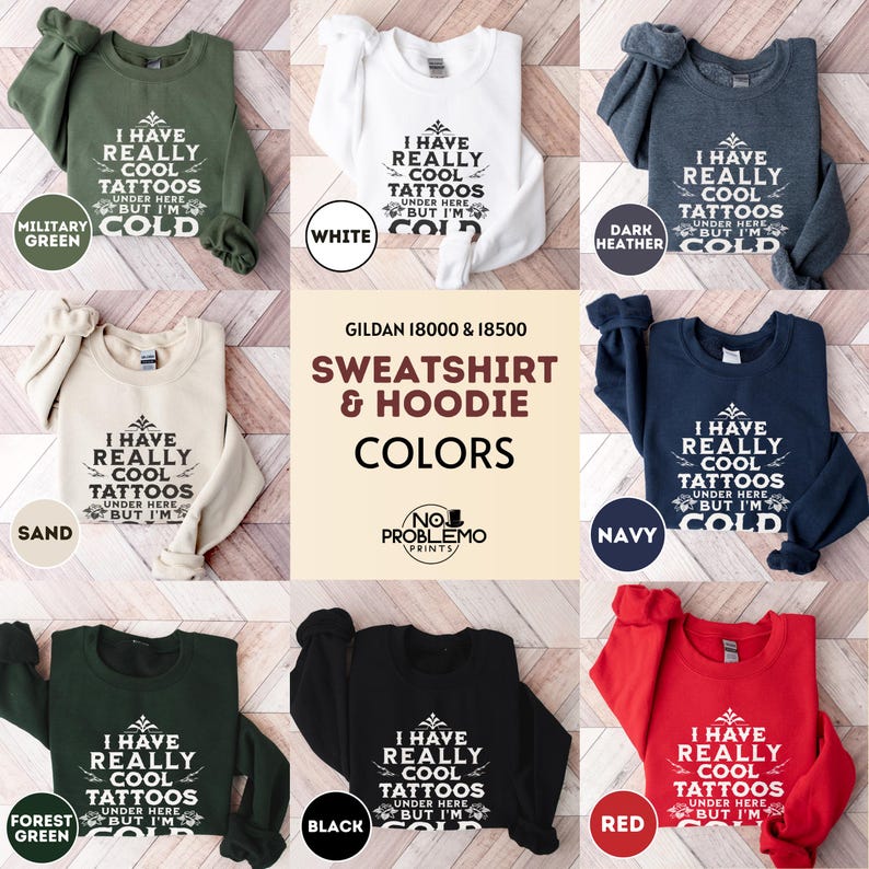 May include: A collection of Gildan 18000 and 18500 sweatshirts and hoodies in military green, white, dark heather, sand, navy, forest green, black, and red. Each garment features the white text I HAVE REALLY COOL TATTOOS UNDER HERE BUT I'M COLD.