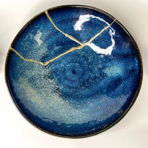 May include: A blue ceramic plate with gold cracks. The plate has a speckled blue and white glaze.
