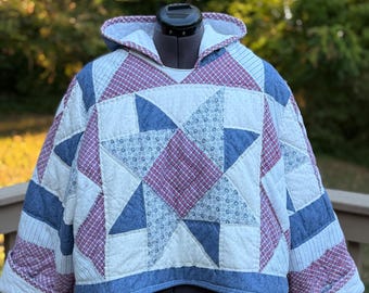 May include: A hooded pullover jacket constructed from quilted fabric featuring a patchwork star pattern. The design incorporates red and white checkered fabric, blue denim-style material, and white fabric with small blue floral prints.