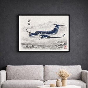 May include: A framed watercolour print depicting a blue and white aircraft flying over a misty landscape. The artwork includes Japanese characters and a signature. The plane has a distinctive logo on its tail.