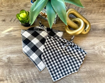 May include: Two black and white gingham dog bandanas. The bandanas are folded and tied together.