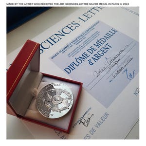 May include: A silver medal in a red box with a certificate that reads "Diplome de Medaille d'Argent" and "A Irina Laramonosn Designer 6 October 2024".