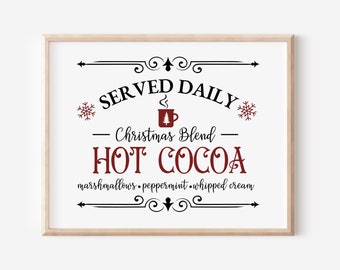 May include: A framed sign with the text "SERVED DAILY - Christmas Blend - HOT COCOA - marshmallows, peppermint, whipped cream" in black and red lettering. The sign has a decorative border and snowflakes.