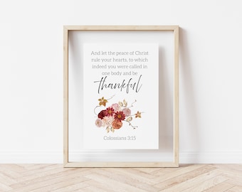 May include: A framed print with the text "And let the peace of Christ rule your hearts, to which indeed you were called in one body and be thankful." Floral arrangement in shades of red, pink, and orange. The text "Colossians 3:15" is at the bottom.
