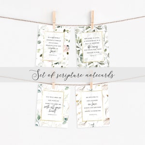 May include: Set of four white notecards with gold trim and floral designs. Each card features a different Bible verse. The verses are: "Be completely humble and gentle; be patient, bearing with one another in love." (Ephesians 4:2), "The Lord is good, a stronghold in a day of distress. He cares for those who take refuge in him." (Nahum 1:7), "You will seek me and find me when you seek me with all your heart." (Jeremiah 29:13), "Be devoted to one another in love. Honor one another above yourselves." (Romans 12:10)