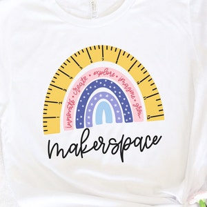 May include: White t-shirt with a rainbow design incorporating a ruler arc. The rainbow includes the words "innovate, create, explore, imagine, grow." The word "makerspace" is written in a script font below the rainbow.
