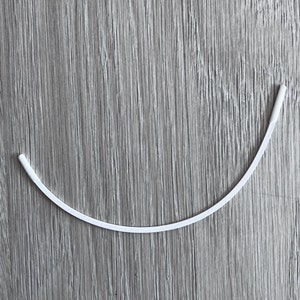 May include: A white, flexible, plastic nose wire for a face mask.