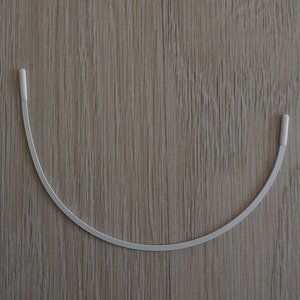 May include: A white metal underwire for a bra.