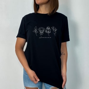 May include: Black t-shirt with a white graphic of five stylized flowers and the word "Inazuma".