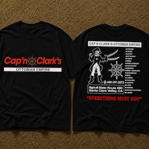 Puede incluir: Una camiseta negra con un gráfico frontal con el texto rojo Cap'n Clark's y el texto blanco Ottoman Empire. La parte posterior muestra una ilustración de un pirata, un timón, una lista de muebles, un número de teléfono y el texto rojo EVERYTHING MUST GO!!