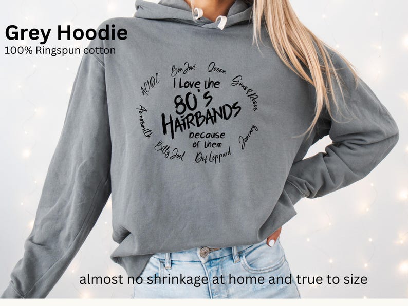 Peut inclure: Un sweat &agrave; capuche gris en 100% coton ringspun. Le devant affiche le texte "I Love the 80's Hairbands because of them" dans un design circulaire, avec des noms de groupes comme Bon Jovi et Def Leppard. Le texte "Grey Hoodie" est en haut.