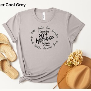 Peut inclure: T-shirt gris clair avec l'inscription "I love the 80's Hairbands because of them" dans un cercle. Le t-shirt est associ&eacute; &agrave; des sandales en osier et un chapeau marron.