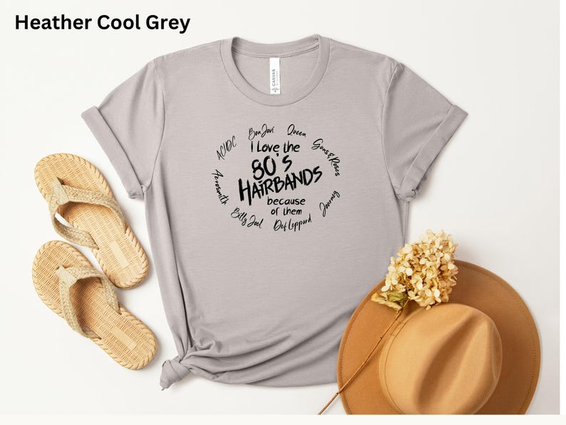 Peut inclure: T-shirt gris clair avec l'inscription "I love the 80's Hairbands because of them" dans un cercle. Le t-shirt est associ&eacute; &agrave; des sandales en osier et un chapeau marron.