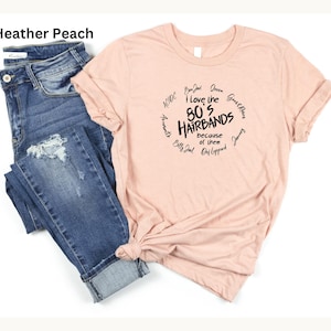Peut inclure: Un t-shirt p&ecirc;che avec le texte "I love the 80's Hairbands because of them" dans un design circulaire. Le t-shirt est associ&eacute; &agrave; un jean bleu avec des d&eacute;tails d&eacute;chir&eacute;s.