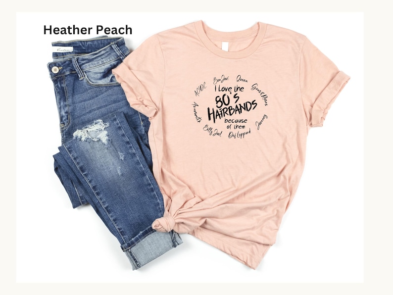 Peut inclure: Un t-shirt p&ecirc;che avec le texte "I love the 80's Hairbands because of them" dans un design circulaire. Le t-shirt est associ&eacute; &agrave; un jean bleu avec des d&eacute;tails d&eacute;chir&eacute;s.