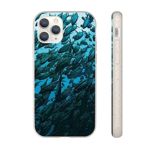 Puede incluir: Una funda de teléfono blanca con una ilustración azul y verde de un banco de peces. La funda tiene un recorte para el objetivo de la cámara.