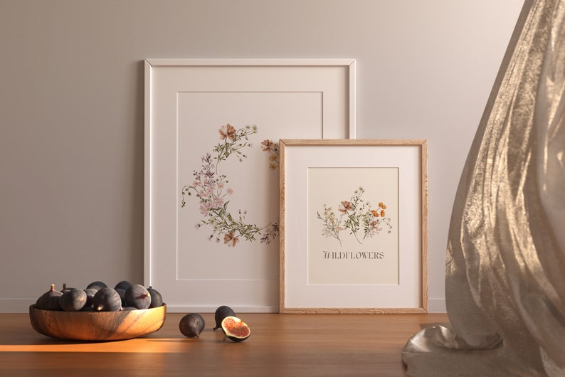 Puede incluir: Dos impresiones bot&aacute;nicas enmarcadas con ilustraciones de flores silvestres. La impresi&oacute;n m&aacute;s grande presenta una corona de flores silvestres, mientras que la impresi&oacute;n m&aacute;s peque&ntilde;a muestra un grupo de flores silvestres con el texto "Flores silvestres" debajo.