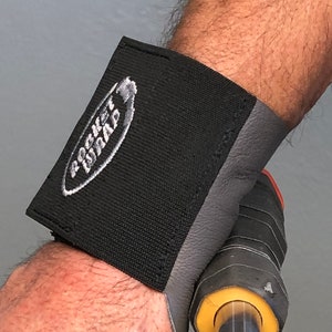 May include: A black wrist wrap with gray padding and the text "Pocket Wrap" in white. The wrap is worn on a person's wrist.