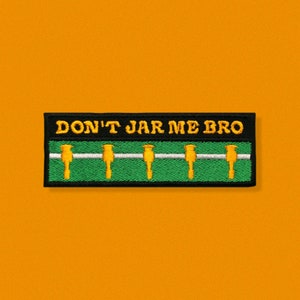 May include: Embroidered patch with the text "DON'T JAR ME BRO" in yellow on a black background. The patch features a foosball table design with yellow players on a green field, and a white bar.
