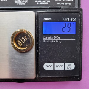 K&ouml;nnte beinhalten: Eine digitale Waage mit einem goldfarbenen Objekt auf der Plattform. Die Waage zeigt 2,9 Gramm an. Die Waage hat ein schwarzes Display mit wei&szlig;em Text, auf dem "AWS-600" und "Kapazit&auml;t: 600 g Aufl&ouml;sung: 0,1 g" steht. Die Waage hat drei Tasten mit den Beschriftungen "TARE", "MODE" und "EIN/AUS".