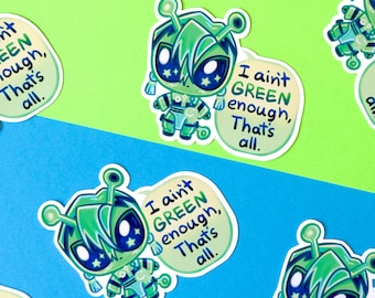 May include: A collection of stickers featuring a cartoon alien character in shades of green and blue. The alien has large eyes with star-shaped pupils and is wearing a futuristic outfit. Each sticker includes the text, "I ain't GREEN enough, That's all."