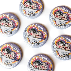 May include: Several round buttons with the text "Enemies to Lovers" and a cartoon illustration of two figures with angel wings. The design features a rainbow arc and hearts.