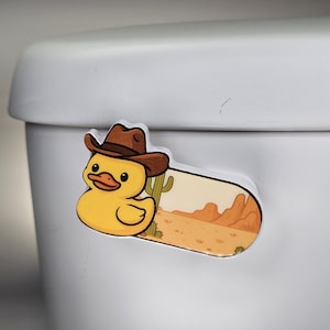 May include: A yellow duck wearing a brown cowboy hat, with a desert scene background. The sticker is a fun, cartoonish design, perfect for adding a touch of whimsy to any surface.