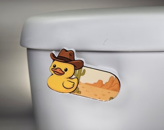 May include: A yellow duck wearing a brown cowboy hat, with a desert scene background. The sticker is a fun, cartoonish design, perfect for adding a touch of whimsy to any surface.