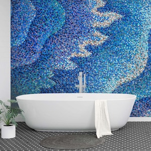 Puede incluir: Una bañera blanca con una toalla colgando del borde, situada frente a una pared cubierta de azulejos de mosaico azul.