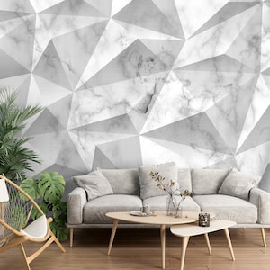 May include: A white and gray geometric patterned wallpaper with a white sofa, a wooden chair, and plants in front of it.