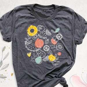 May include: A dark gray t-shirt with a white graphic design of various fruits, including watermelon, pineapple, kiwi, and oranges.