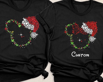 Puede incluir: Dos camisetas negras de manga corta con un gráfico de una silueta de cabeza de ratón compuesta por puntos rojos, verdes y blancos. La camiseta izquierda tiene un gorro de Papá Noel, la derecha tiene un gorro y la palabra Custom debajo.