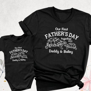 May include: Two black t-shirts with a white graphic of turtles and the text "Our First Father's Day Together 2024 Daddy & Bailey"
