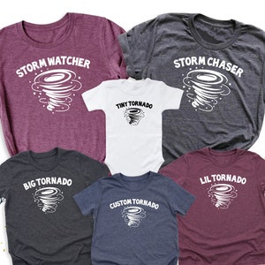 May include: Five t-shirts with a tornado graphic and text. The shirts are in different colors and sizes. The text on the shirts reads "Storm Watcher", "Storm Chaser", "Tiny Tornado", "Big Tornado", "Lil Tornado", and "Custom Tornado".