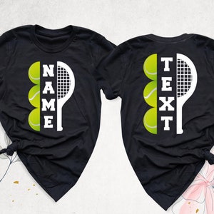 May include: Two black t-shirts with a white tennis racket and tennis balls forming the words "NAME" and "TEXT".
