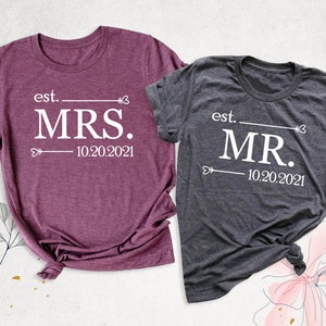 K&ouml;nnte beinhalten: Zwei T-Shirts, eines in Rotbraun und eines in Grau, mit dem Aufdruck "est. MRS. 10.20.2021" und "est. MR. 10.20.2021".